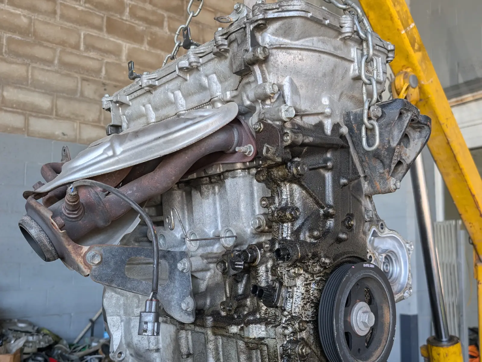 Toyota hybrid engine suspended on hoist with transmission assembly